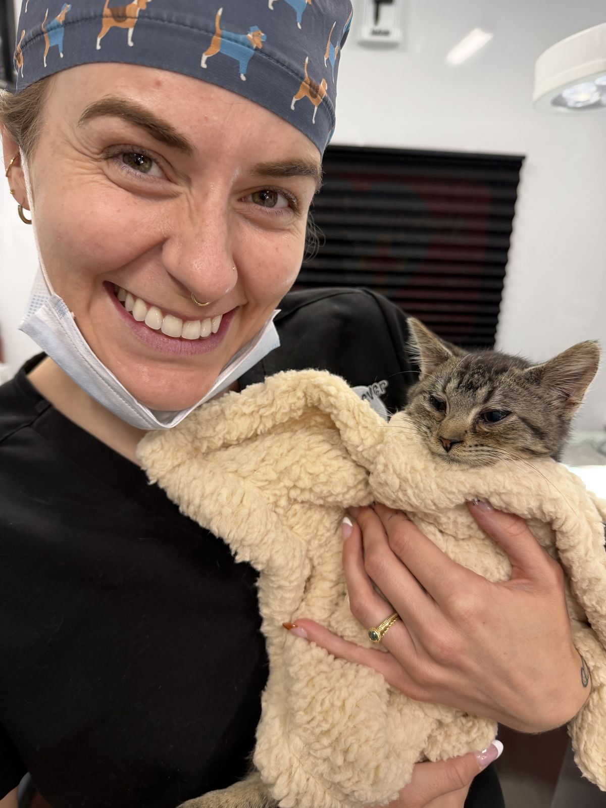 A veterinary professional smiling while holding a cat after care